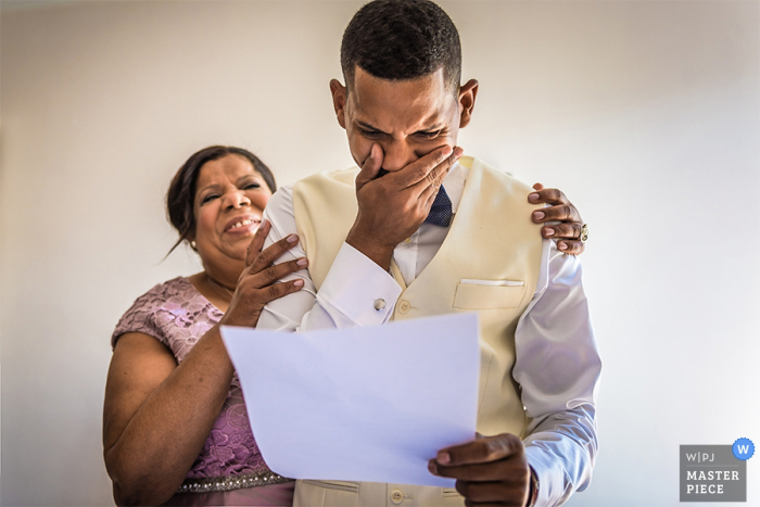 Photo by: <a href="https://www.wpja.com/contests/2016-q3-photography-contest/getting-ready/1912396">Dimitri Voronov - Spain</a> Photo of a woman holding the groom as he tears up reading a letter - Image by a Barcelona wedding photographer.
