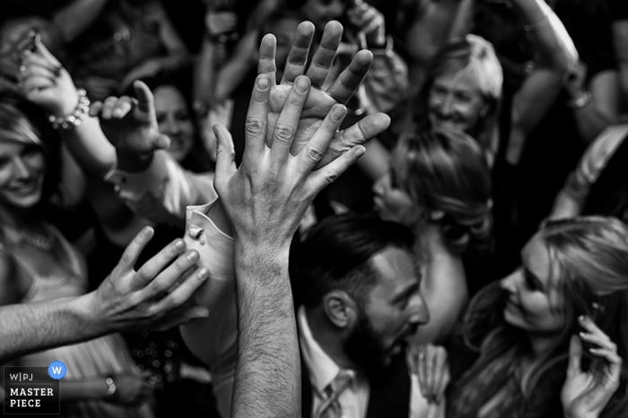 Black and white detail photo of a crowd people raising their hands and high-fiving by a Carson City, NV wedding photographer.