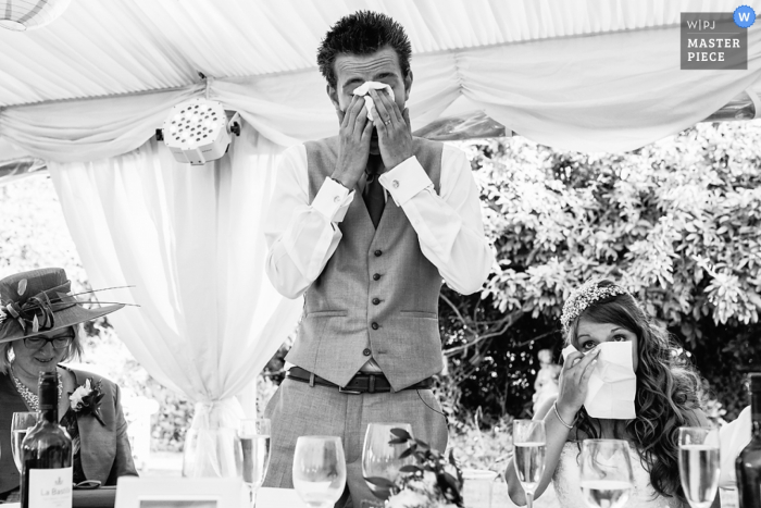 Photo by: <a href="https://www.wpja.com/contests/2016-q4-photography-competition/toastingspeeches/1934506">Richard Howman - United Kingdom</a> Black and white photo of the bride and groom getting tearful during a speech by a Bristol, England wedding reportage photographer.