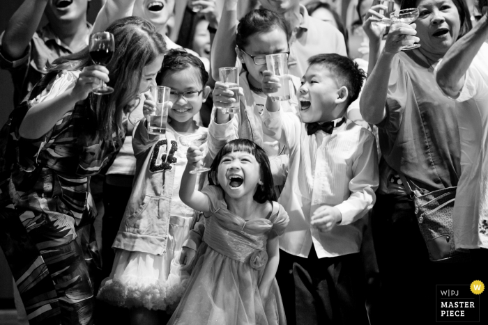 Photo by: <a href="https://www.wpja.com/contests/2016-q4-photography-competition/toastingspeeches/1945921">Chin Whei Tay - Malaysia</a> Black and white photo of children holding up their glasses during a toast by a Malaysia wedding photographer.