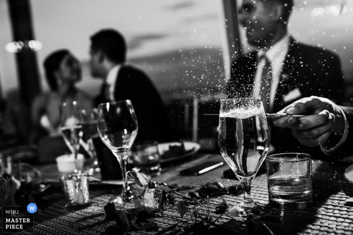 A foto preto e branco do detalhe da água que espirra fora de um vidro como um convidado bate-o com uma faca por um fotógrafo do casamento de Washington, CC