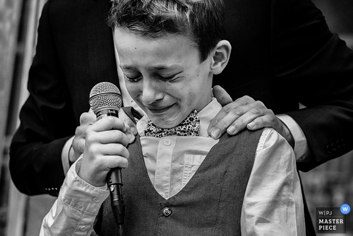 Photo by: <a href="https://www.wpja.com/contests/2016-q4-photography-competition/toastingspeeches/1963581">Philip Stephenson - France</a> A young boy gets emotional during the speech in this black and white photo by a Paris wedding photographer.