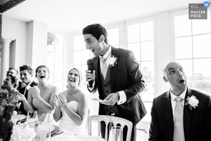 Photo by: <a href="https://www.wpja.com/contests/2016-q4-photography-competition/toastingspeeches/1971541">Paul Tansley - United Kingdom</a> The best man has the bridal party laughing during his speech in this black and white photo by a Hampshire, England wedding reportage photographer.