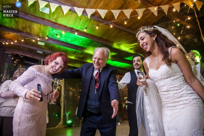 A woman shows the bride a picture on her phone during the reception in this photo by an Armenia wedding photographer.