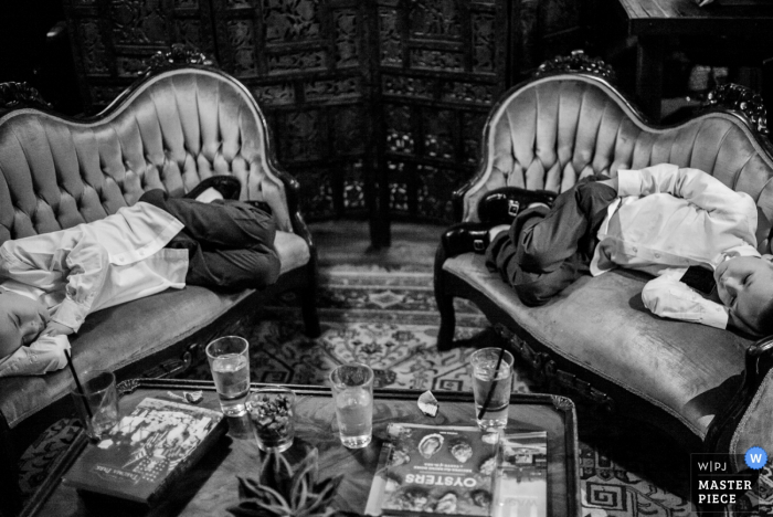 Photo by: <a href="https://www.wpja.com/contests/2016-q4-photography-competition/symmetry/1972366">Philip Thomas - United States</a> Black and white photo of two young guests resting on love seats by a San Antonio, TX wedding photographer.