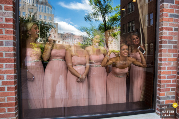 Photo by: <a href="https://www.wpja.com/contests/2016-q4-photography-competition/humor/1961206">Greg Burnett - United States</a> Photo of bridesmaids in their matching, pink dresses looking through a large window by a Cincinnati, OH wedding photographer.