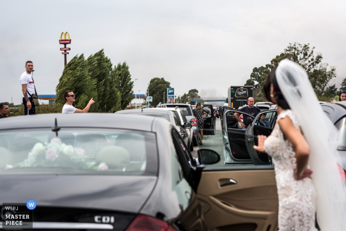 Photo by: <a href="https://www.wpja.com/contests/2016-q4-photography-competition/humor/1964371">Matteo Del Vecchio - Italy</a> The bride stands outside of her car waiting in traffic in this photo by a Latina, Italy wedding photographer.