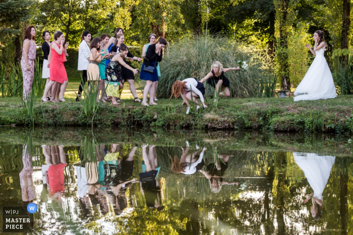 Der Hochzeitsfotograf von Montpellier hat dieses humorvolle Foto von Hochzeitsgästen aufgenommen, die beinahe in einen Teich gefallen wären, um den Brautstrauß einzufangen