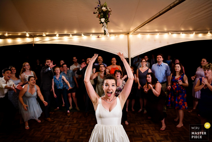 Photo de la mariée qui lance son bouquet aux invités derrière elle par un photographe de mariage à Burlington, dans le Vermont.