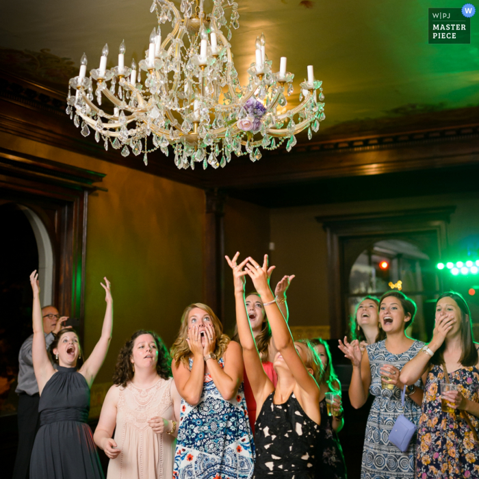 Foto de mulheres esperando pegar o buquê da noiva enquanto ele voa pelo ar, feita por um fotógrafo de casamento em Minneapolis, MN.