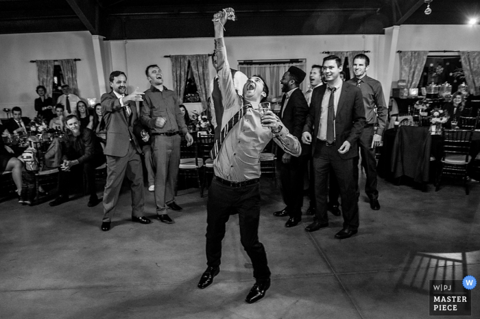 Photo by: <a href="https://www.wpja.com/contests/2016-q4-photography-competition/bouquetgarter-action/1961086">James Nix - United States</a> Black and white photo of a man celebrating catching the garter by a Charlotte, NC wedding photographer.