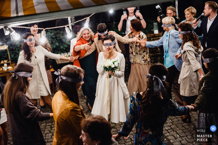 Photo de la mariée et des invités les yeux bandés pendant que la mariée se prépare à lancer son bouquet par un photographe de mariage russe.