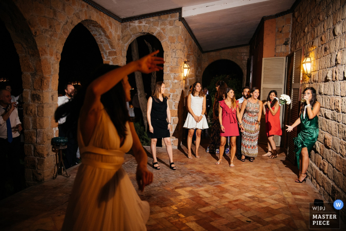 A noiva joga seu buquê branco por cima do ombro nesta foto tirada por um fotógrafo de casamento em Roma.