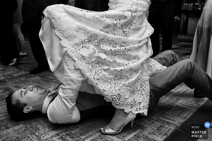 Black and white photo of the groom removing his bride's garter by a Carson City, NV wedding photographer.