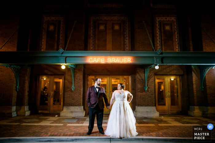 Chicago wedding photographer created this portrait of a bride and groom holding hands outside a cafe at night