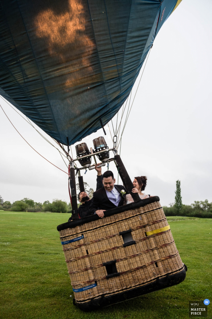 San Francisco wedding photographer captured this image of a bride and groom taking off in a hot air balloon on a cloudy day 