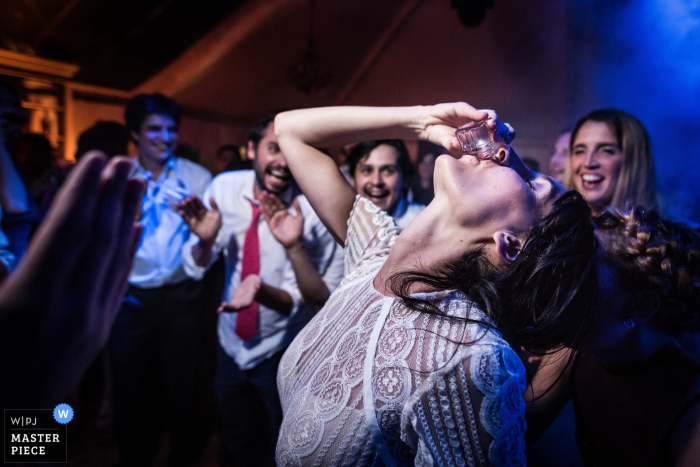 Santa Fe wedding photographer captured this humorous image of a bride taking a shot while the guests cheer her on. 