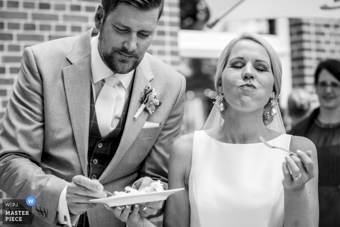 El fotógrafo de bodas de Overjissel capturó esta foto en blanco y negro de una novia y un novio disfrutando de su pastel de bodas en su recepción al aire libre