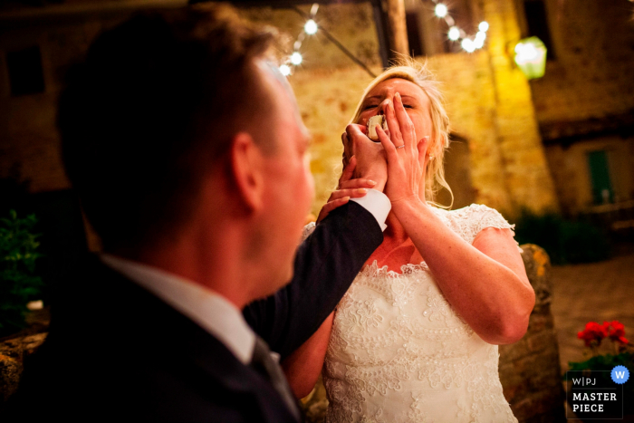 Florence wedding photographer captured this silly image of a groom smashing wedding cake into the brides face.