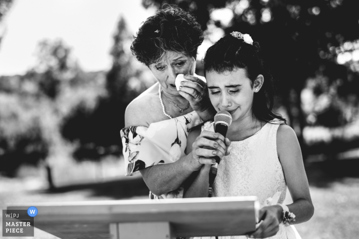 Lot-et-Garonne wedding photographer captured this black and white emotional image of a young girl getting assistance reading her wedding speech 