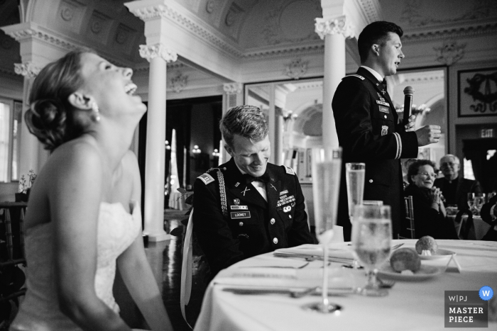 Saratoga wedding photographer captured this black and white photo of a bride and her serviceman groom laughing during speeches at their reception