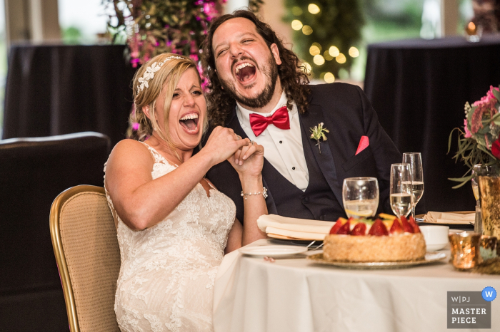 Cleveland bride and groom laughing hysterically at their reception Cleveland wedding photographer capture this image of the bride and groom laughing hysterically at their reception