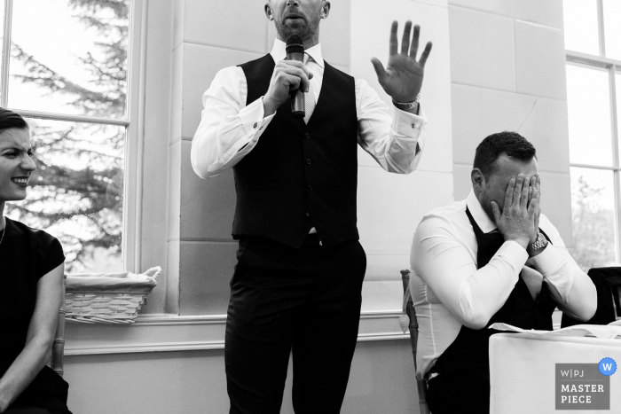 Photo by: <a href="https://www.wpja.com/contests/2017-tri2-photography-competition/toastingspeeches/2022241">Martin Makowski - United Kingdom</a> Nottinghamshire wedding photographer created this black and white photo of the groom covering his face in mortification as the best man gives his speech