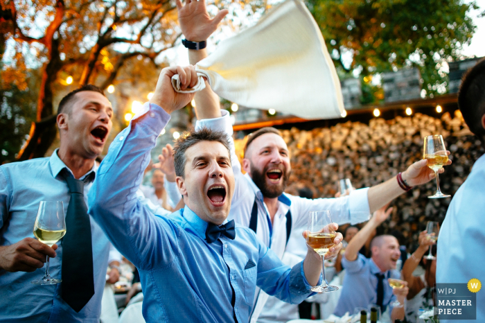 Der Hochzeitsfotograf aus Rom hat dieses Foto von drei ausgelassenen Trauzeugen aufgenommen, die beim Hochzeitsempfang anstoßen, während sie den Reden lauschen