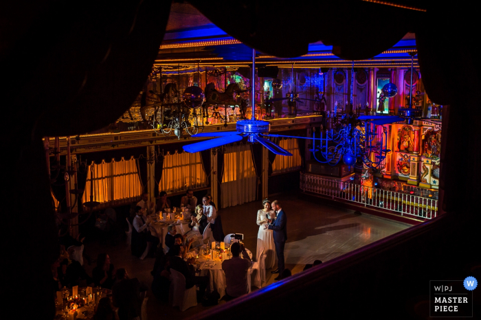 From a distance, France wedding photographer captured the parents of the bride giving their speeches under the glow of purple lights