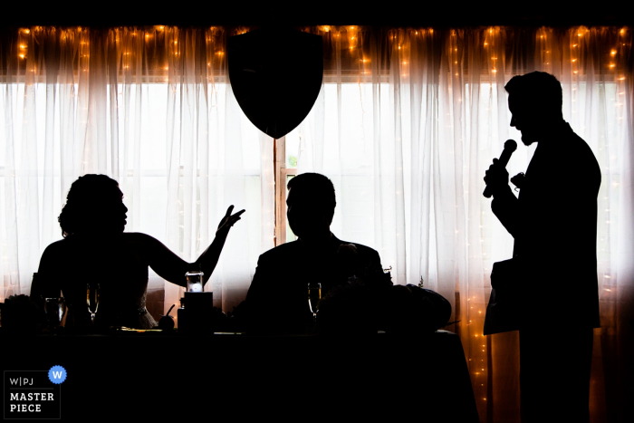 The silhouettes of the bride and groom in front of a curtain of twinkle lights was captured by a New Jersey wedding photographer