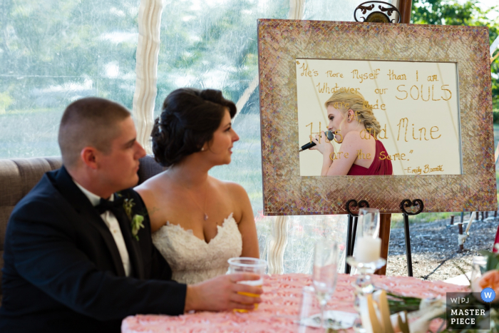 Der Hochzeitsfotograf aus Maine hat dieses Foto der Braut und des Bräutigams aufgenommen, die während ihrer Zeremonie aufmerksam den Röstreden zuhörten