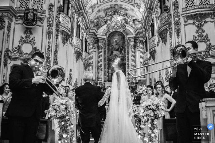 Photo par: <a href="https://www.wpja.com/contests/2017-tri2-photography-competition/symmetry/2054261"> Clara Sampaio - Brésil </a> La photographe de mariage de Rio de Janiro a capturé cette image cathédrale noir et blanc d'une mariée que son père a marché dans l'allée tandis que des joueurs de trombone se produisent de chaque côté
