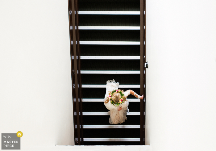Photo by: <a href="https://www.wpja.com/contests/2017-tri2-photography-competition/minimalism/2058651">Tara Theilen - United States</a> Carson City wedding photographer captured this overhead shot of the bride walking on a flight of stairs while wearing a floral crown