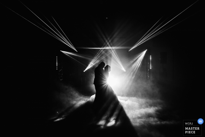 France wedding photographer captured the silhouettes of the bride and groom having their first dance amid spot lights and fog