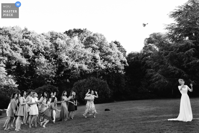 Der Pariser Hochzeitsfotograf hat dieses Schwarz-Weiß-Foto der Braut aufgenommen, wie sie ihren Blumenstrauß auf einer Waldlichtung wirft