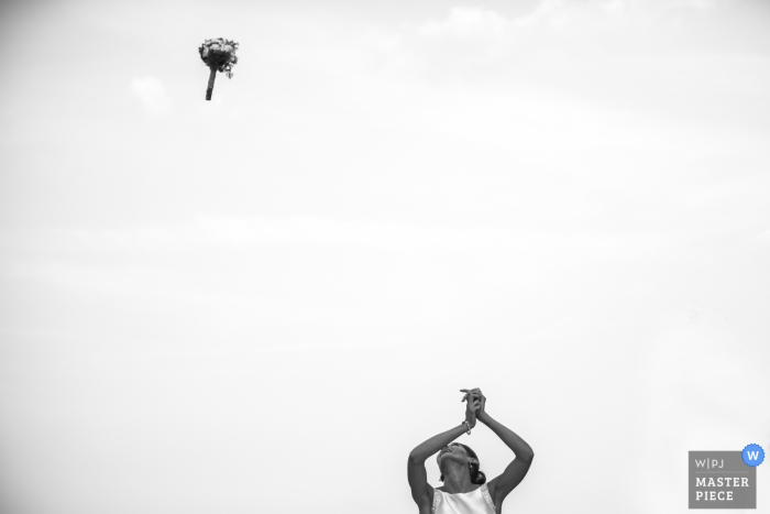 Lecco wedding photographer captured this black and white photo of the bride tossing her bouquet high in an overcast sky