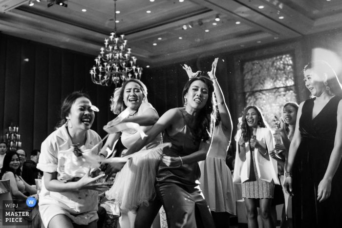 Photo by: <a href="https://www.wpja.com/contests/2017-tri2-photography-competition/bouquetgarter-action/2033766">Ackapol Dhuamrearngrom - Thailand</a> Nonthaburi wedding photographer captured this black and white image of a group of wedding guests competing fiercely to catch the bouquet