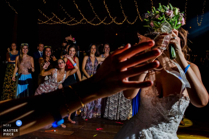 Photo by: <a href="https://www.wpja.com/contests/2017-tri2-photography-competition/bouquetgarter-action/2037711">Omar Berr - Peru</a> Lima wedding photographer captured the wedding guests waiting patiently for the bride to throw her bouquet under strings of twinkling lights