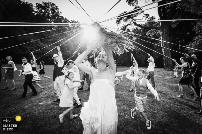 France wedding photographer captured this black and white photo of the bride tossing the bouquet in the middle of a clearing in the woods