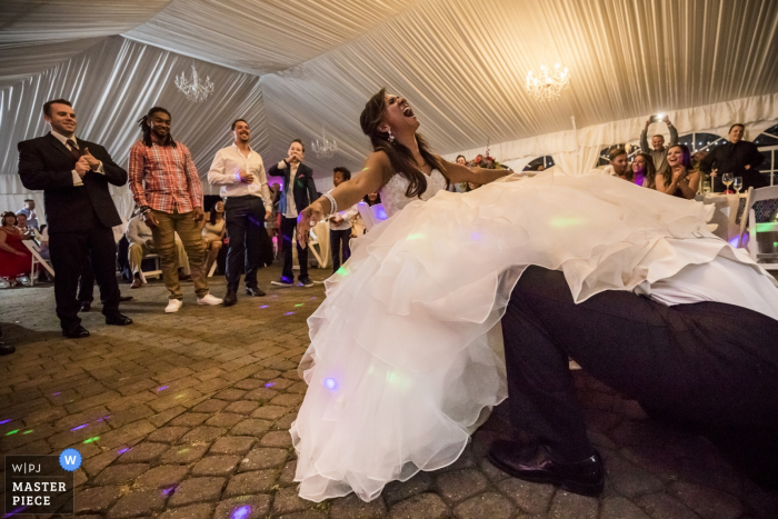 Il fotografo di matrimoni Tacoma ha catturato questa immagine dello sposo perso nell'abito della sposa mentre recupera la giarrettiera dalla sua gamba al loro ricevimento all'aperto