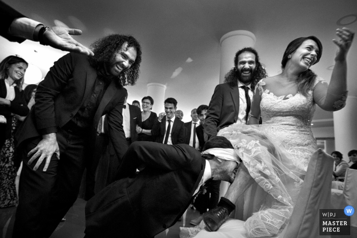 Photo by: <a href="https://www.wpja.com/contests/2017-tri2-photography-competition/bouquetgarter-action/2048786">Danilo Coluccio - Italy</a> Calabria wedding photographer captured this black and white photo of a groom removing the garter from the brides leg while handcuffed and blindfolded