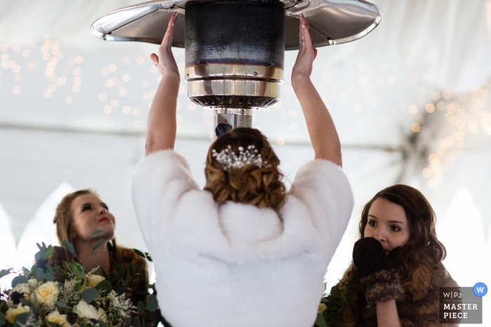 El fotógrafo de bodas de Missoula capturó esta imagen de invitados de bodas vestidos de manopla calentando bajo un calentador grande