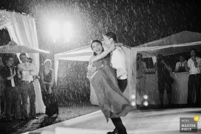 Phuket wedding photographer captured this black and white photo of the groom carrying his bride through rain storm after their ceremony