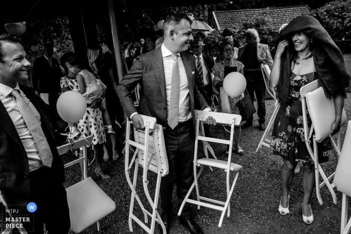 This black and white image of a wedding guests getting rained on at the ceremony was captured by a Flanders wedding photographer 