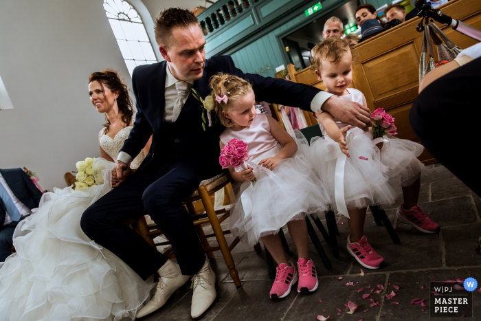 Photo by: <a href="https://www.wpja.com/contests/2017-tri2-photography-competition/flowersdecorations/2047396">Isabelle Hattink - Netherlands</a> Rotterdam wedding photographer captured this photo of flower girls in hot pink tennis shoes and chiffon dresses get some help from the groom when some petals are spilled on the floor