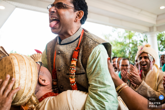 Photo: <a href="https://www.wpja.com/contests/2017-tri2-photography-competition/parents/2029501"> Lauren Brimhall - États-Unis </a> Le photographe de mariage d'Atlantic City a capturé ce marié et son père dans une étreinte émotionnelle tandis que d'autres invités applaudissent à proximité