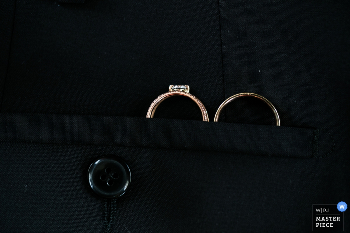 El fotógrafo de bodas de Budapest capturó este detalle de la foto del conjunto de anillos de boda metido de manera segura en el bolsillo de la chaqueta de los novios