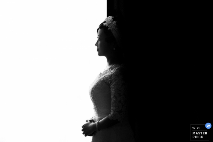 The bride's profile is split down the middle by shadow and light in this black and white photo by a Jiangxi, China wedding photographer.