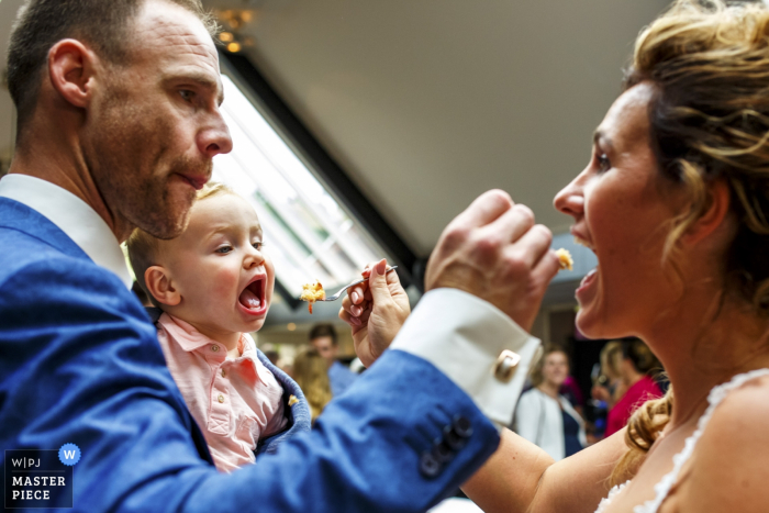 Photo by: <a href="https://www.wpja.com/contests/2017-tri3-photography-competition/food-drinks/2143621">Indra Simons - Netherlands</a> Photo of the groom feeding the bride a bite of cake as she feeds a little boy a bite by a Netherlands wedding photographer.