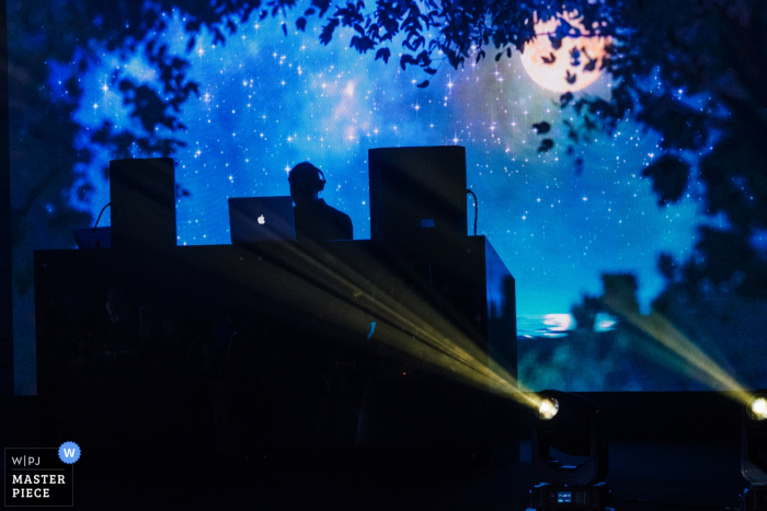 Photo of the DJ silhouetted on an outdoor stage by a Dubai, United Arab Emirates wedding photographer.